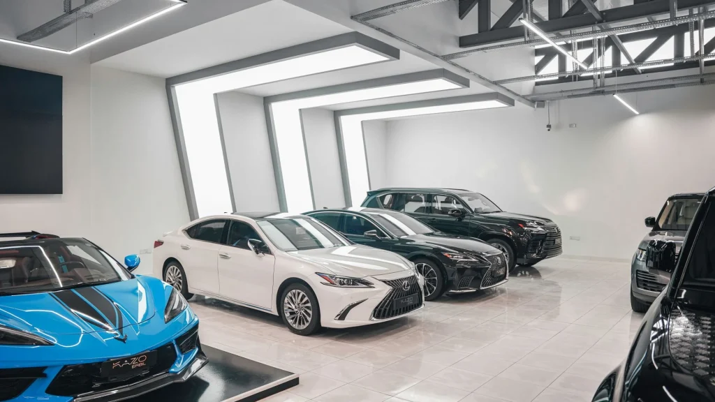Carros premium num showroom moderno — Lexus, Range Rover e Corvette à venda como exemplos de viaturas disponíveis em classificados europeus